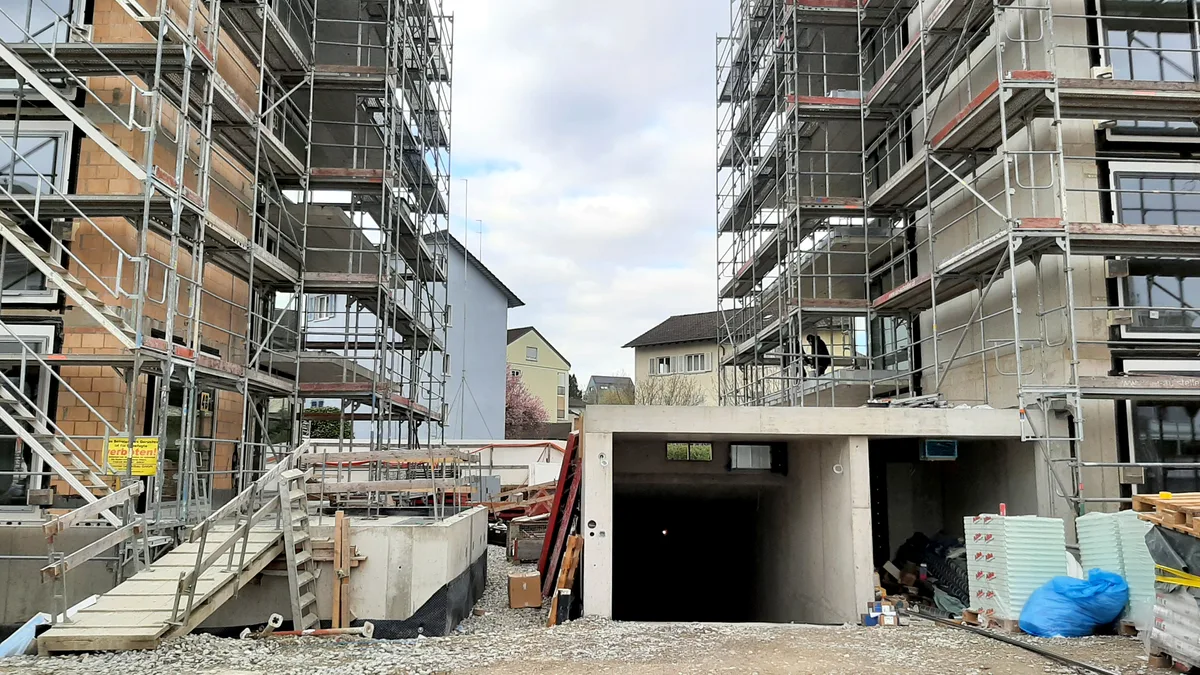 Blick durch zwei Neubauten auf das ursprüngliche Flugfeld-Quartier. Blick auf eine Baustelle in einem Wohnquartier.